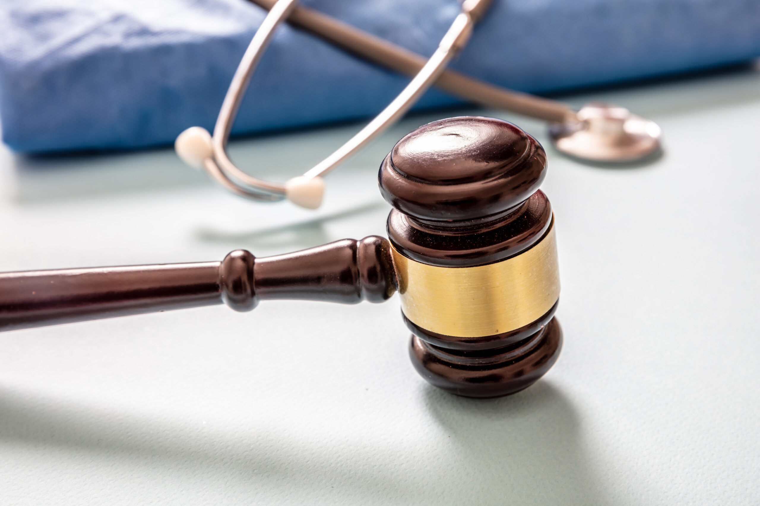 Medical malpractice, personal injury lawyer. Health and Law. Judge gavel, doctor stethoscope and surgeon coat, on white background, close up view