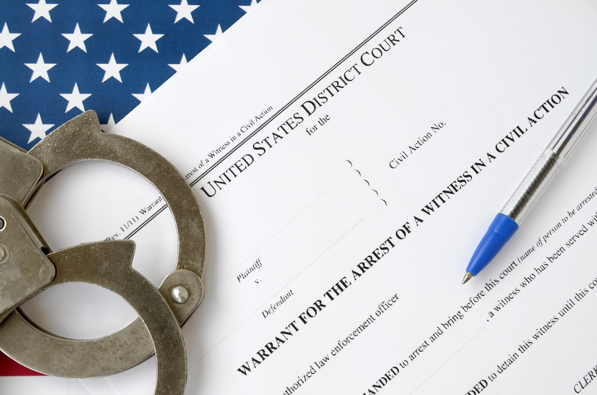 District court warrant for the arrest of a witness in a civil action papers with handcuffs and blue